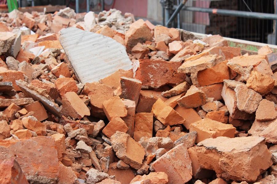 Nahaufnahme von Bauschutt aus zerbrochenen roten Ziegeln und Betonresten in einem Abbruchcontainer.