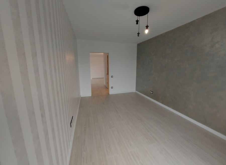 Fertig renovierter Innenraum mit Streifentapete, Spachteltechnik-Wand und neuem Laminatboden.