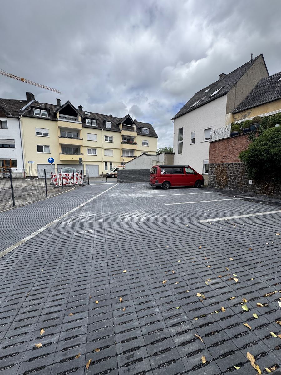 Großer frisch gepflasterter Parkplatz mit Rasengitter-Ökopflaster zwischen Wohnhäusern.
