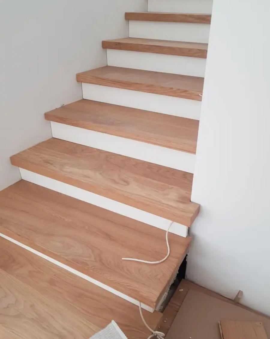 Innentreppe mit neuen Eichenholz-Stufen und weißen Setzstufen, Montage fast fertig.