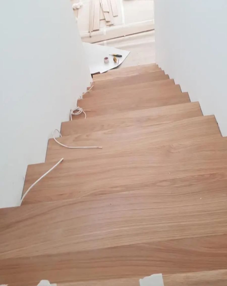 Innentreppe frisch mit hellem Holzdekor-Vinyl belegt, noch mit Kabeln und Werkzeug vom Einbau.